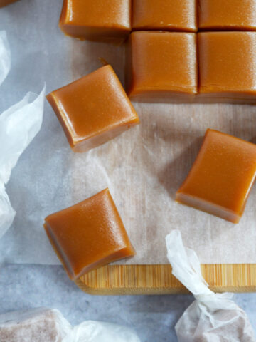 cut homemade caramels on a parchment lined cutting board