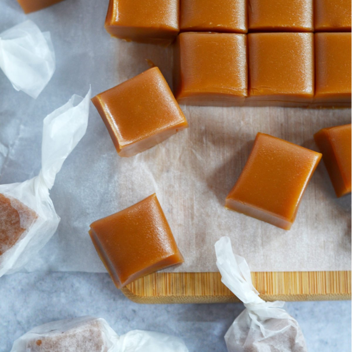 cut homemade caramels on a parchment lined cutting board