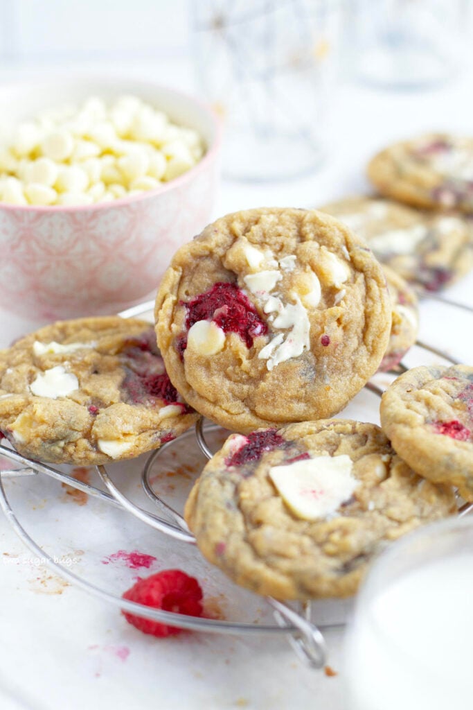 white chocolate raspberry cookies on a cooling rack with a bowl of white chocolate chips