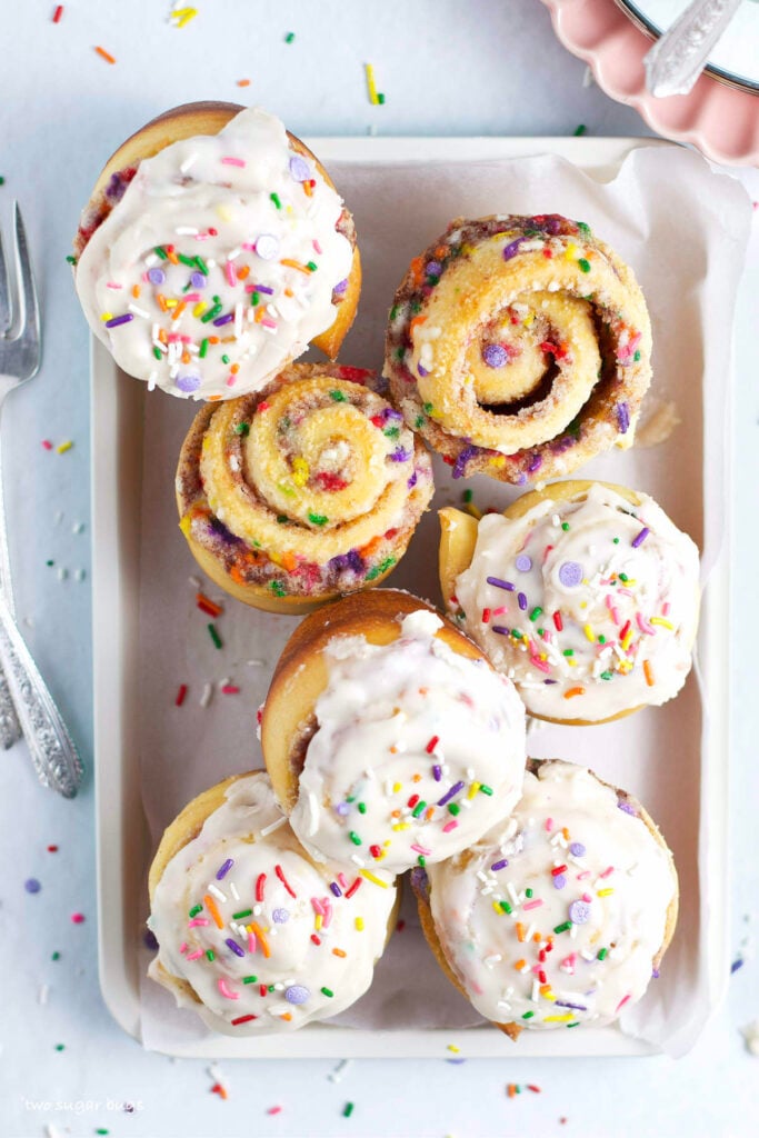 funfetti cinnamon rolls on a tray with plates and forks
