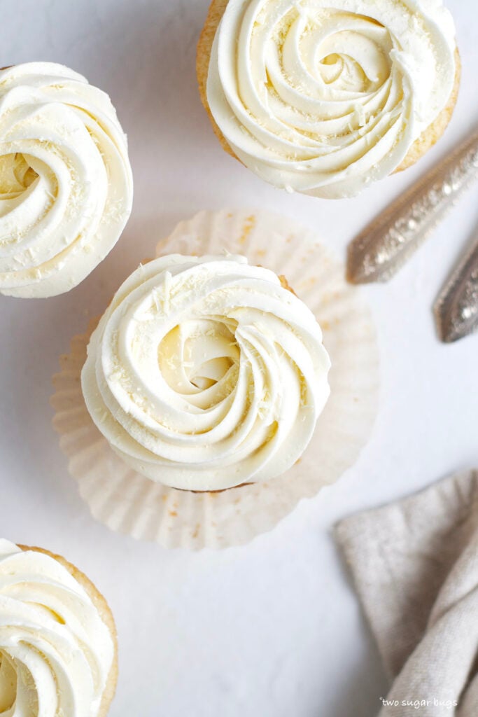 overhead look at four white chocolate cupcakes with buttercream swirls