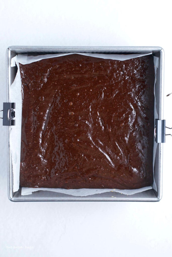 brownie batter on top of shortbread crust in a baking pan