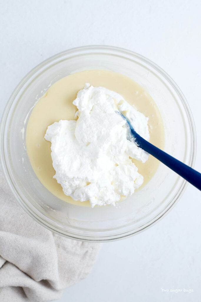 whipped cream being added to sweetened condensed milk