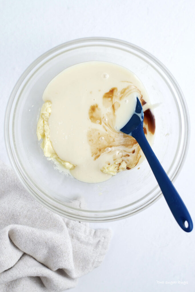 condensed milk and vanilla being added to melted white chocolate and cream cheese