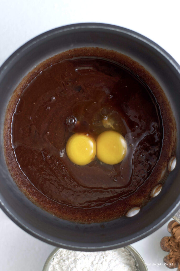 eggs and vanilla on top of melted butter and chocolate in a pot