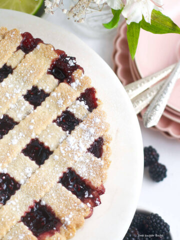 blackberry crostata on a serving plate with plates and forks