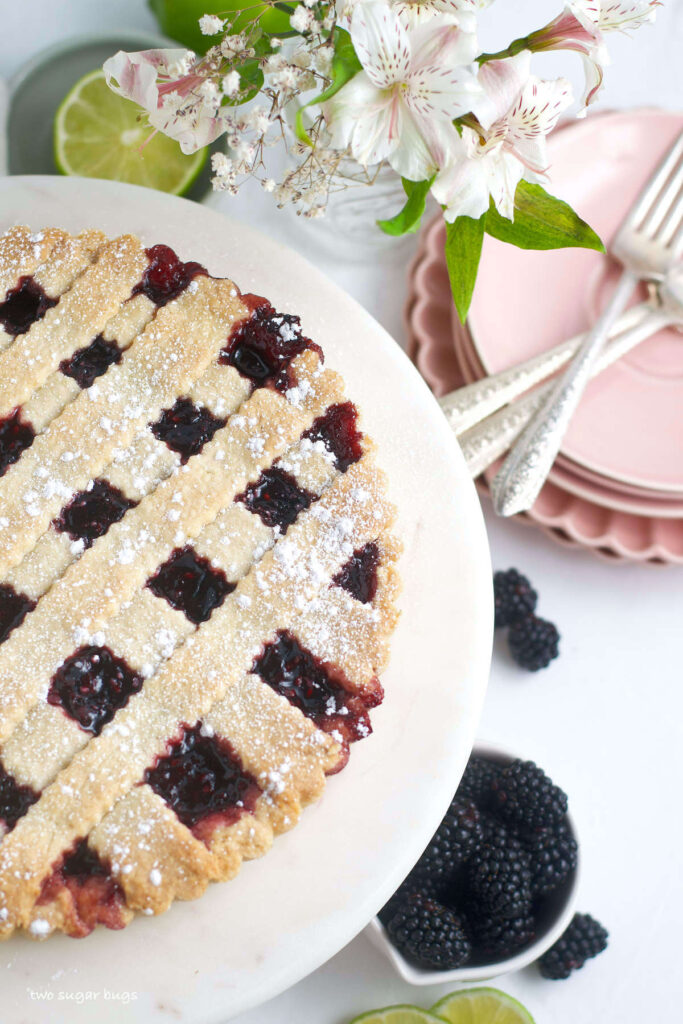 blackberry crostata on a serving plate with plates and forks