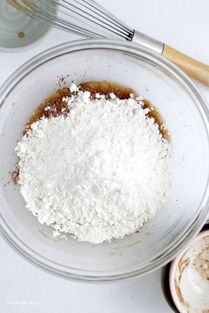 cocoa powder and heat treated flour added to wet ingredients in a bowl