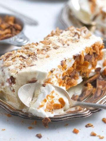 slice of butterfinger ice cream cake on a plate with a spoon