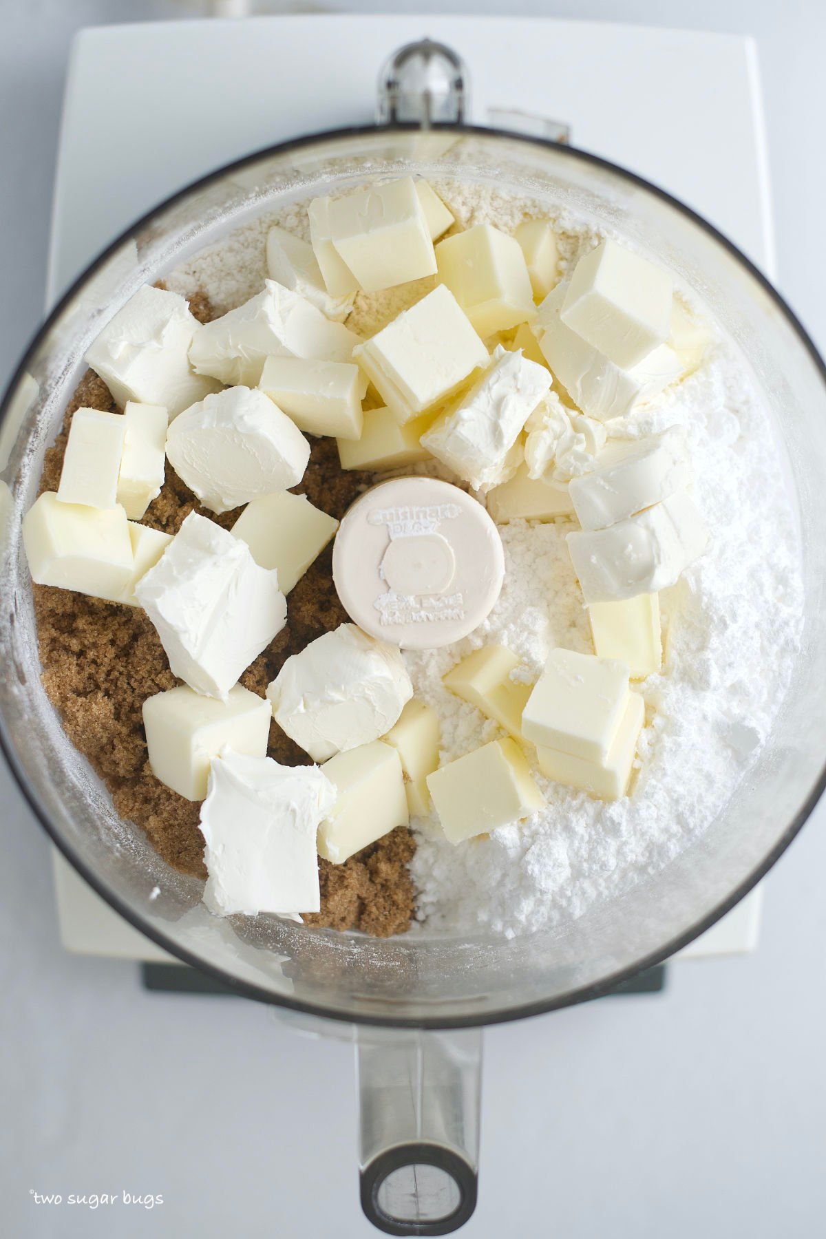 cream cheese and butter on top of sugars and flour in a food processor