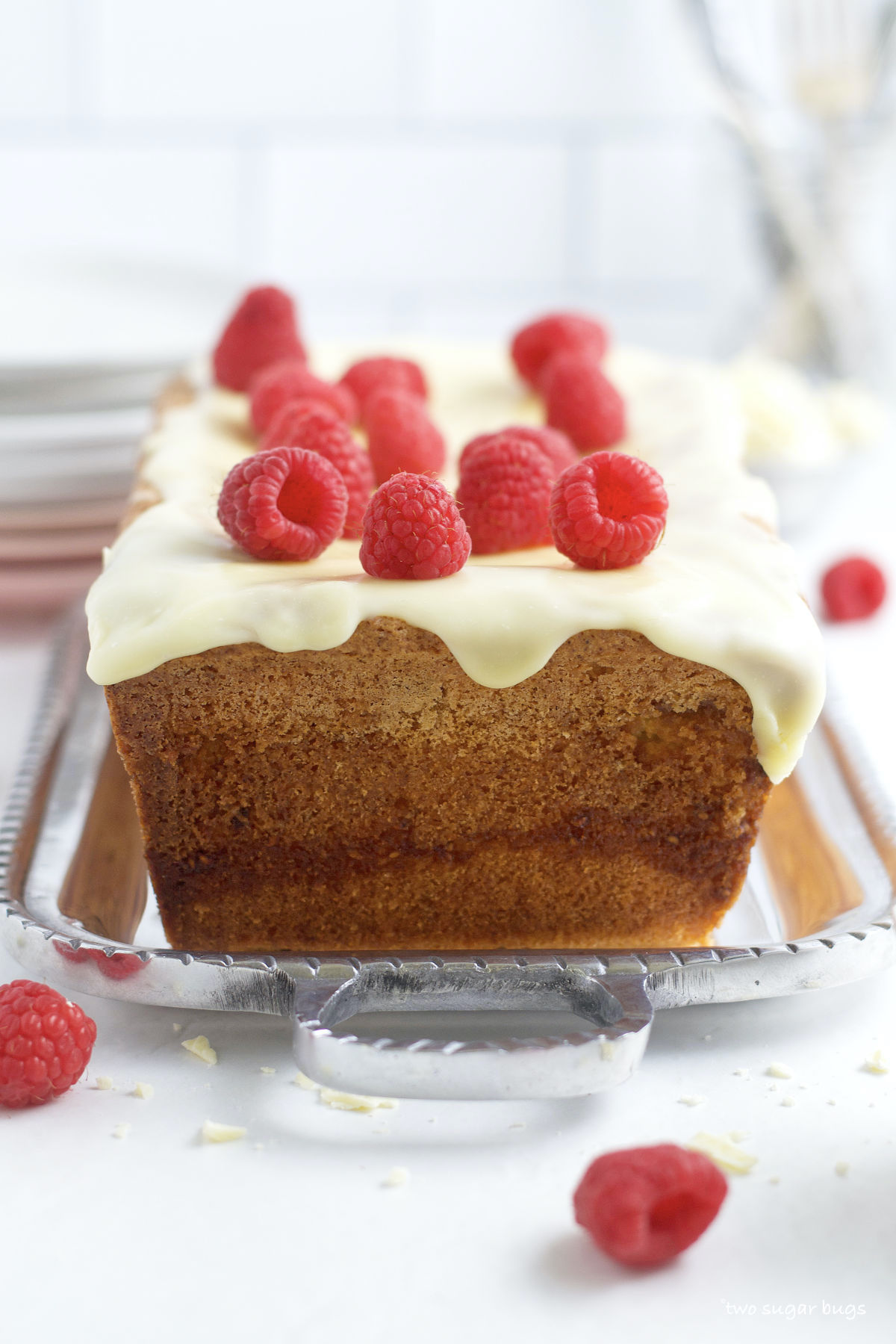 raspberry white chocolate loaf cake with fresh raspberries on a serving tray
