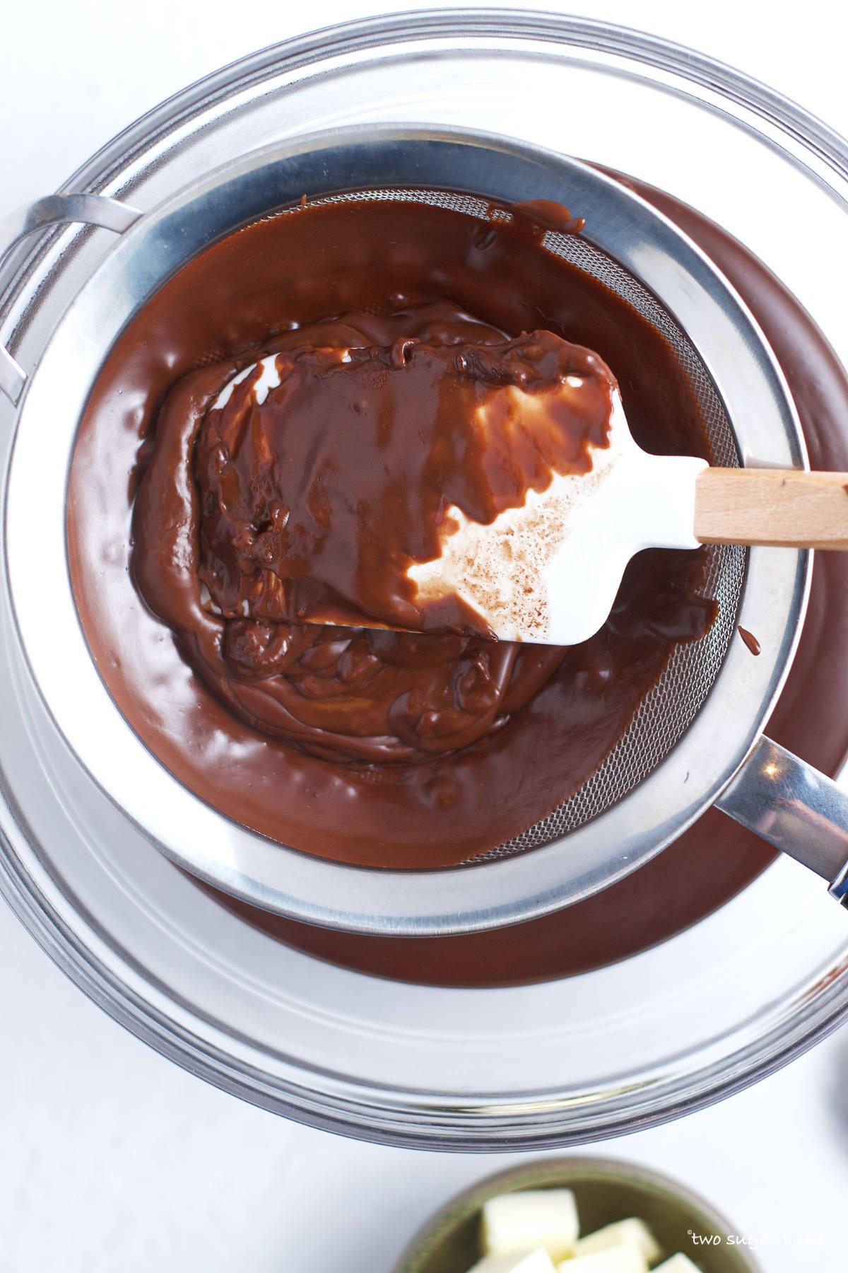 spatula pressing the chocolate pudding through a fine mesh sieve