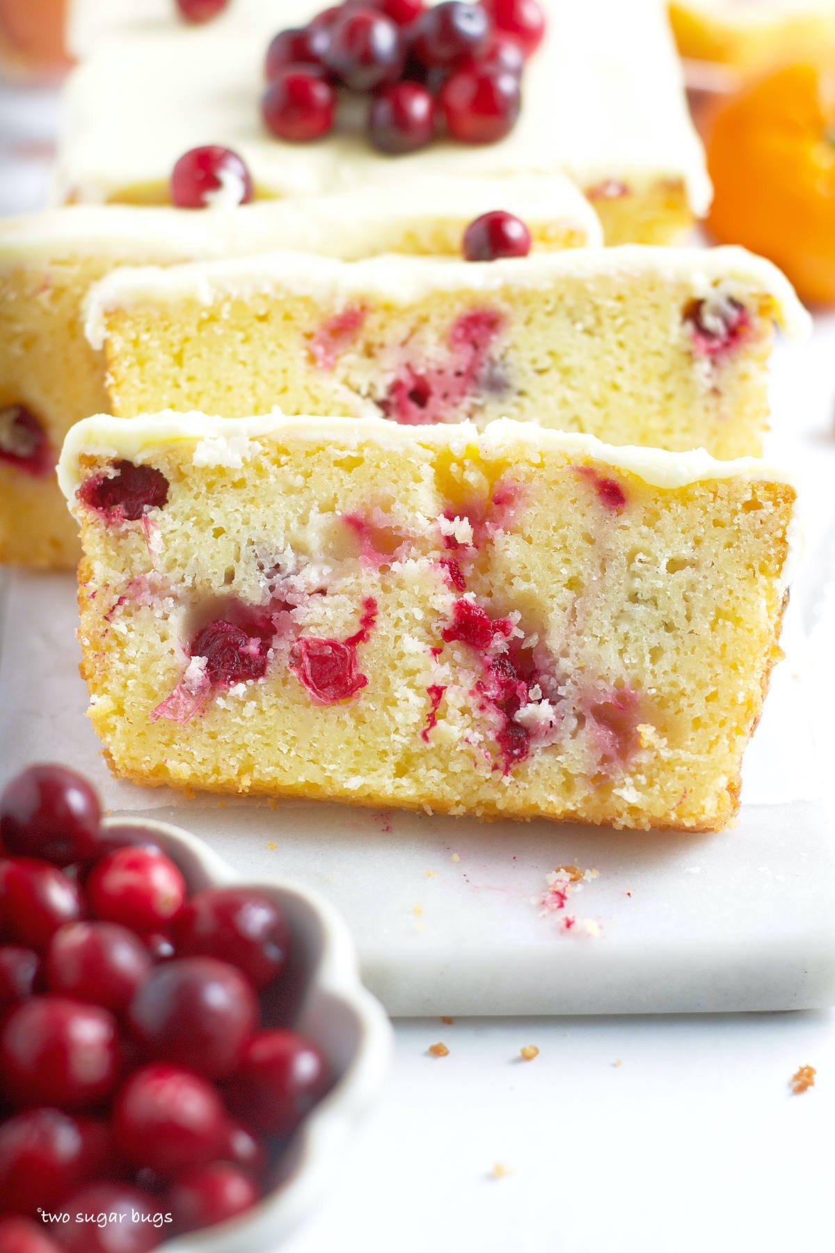 slices of orange cranberry cake with a bowl of cranberries