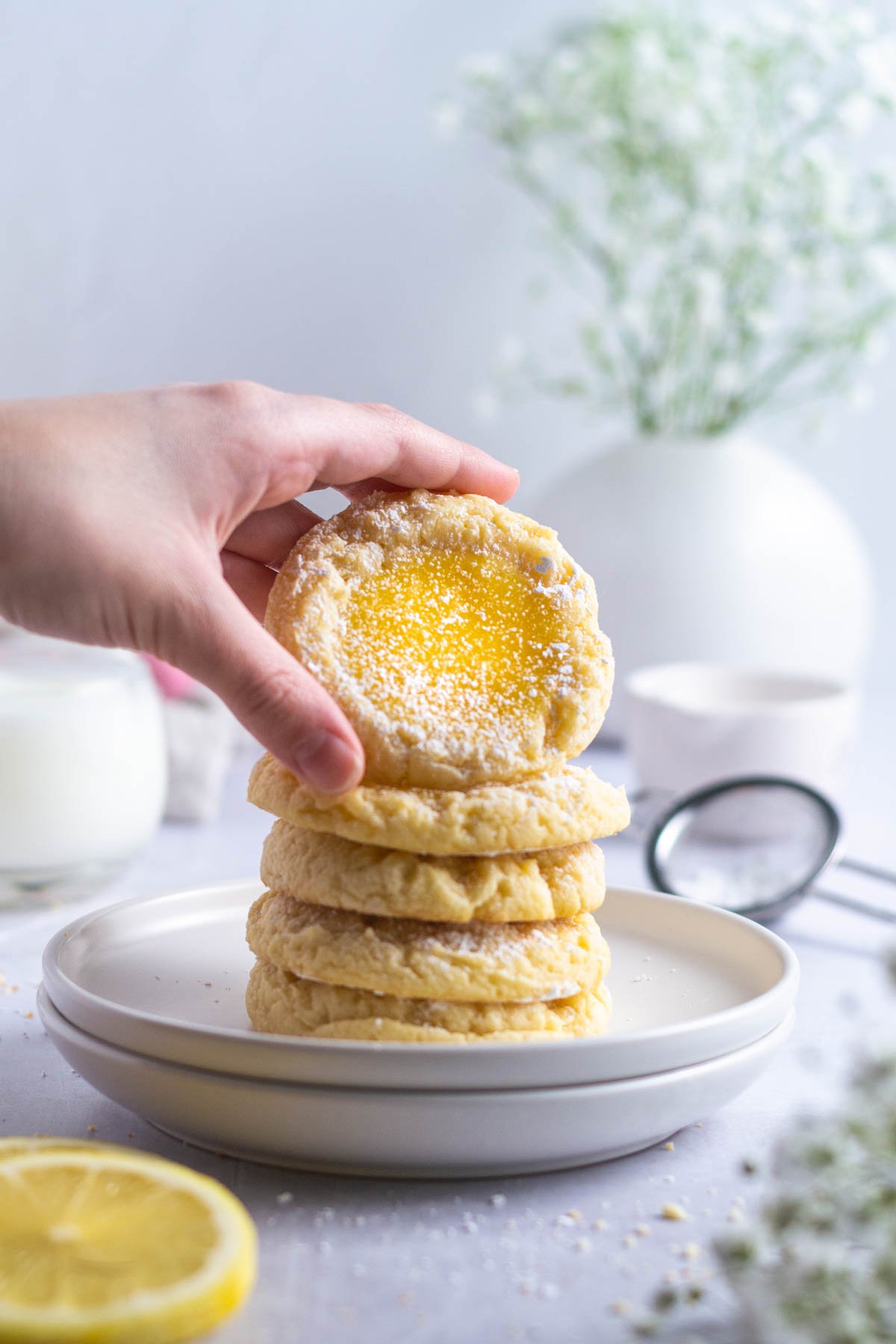 hand grabbing a cookie off a stack of lemon bar cookies