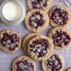cookies on a parchment lined baking sheet with a glass of milk