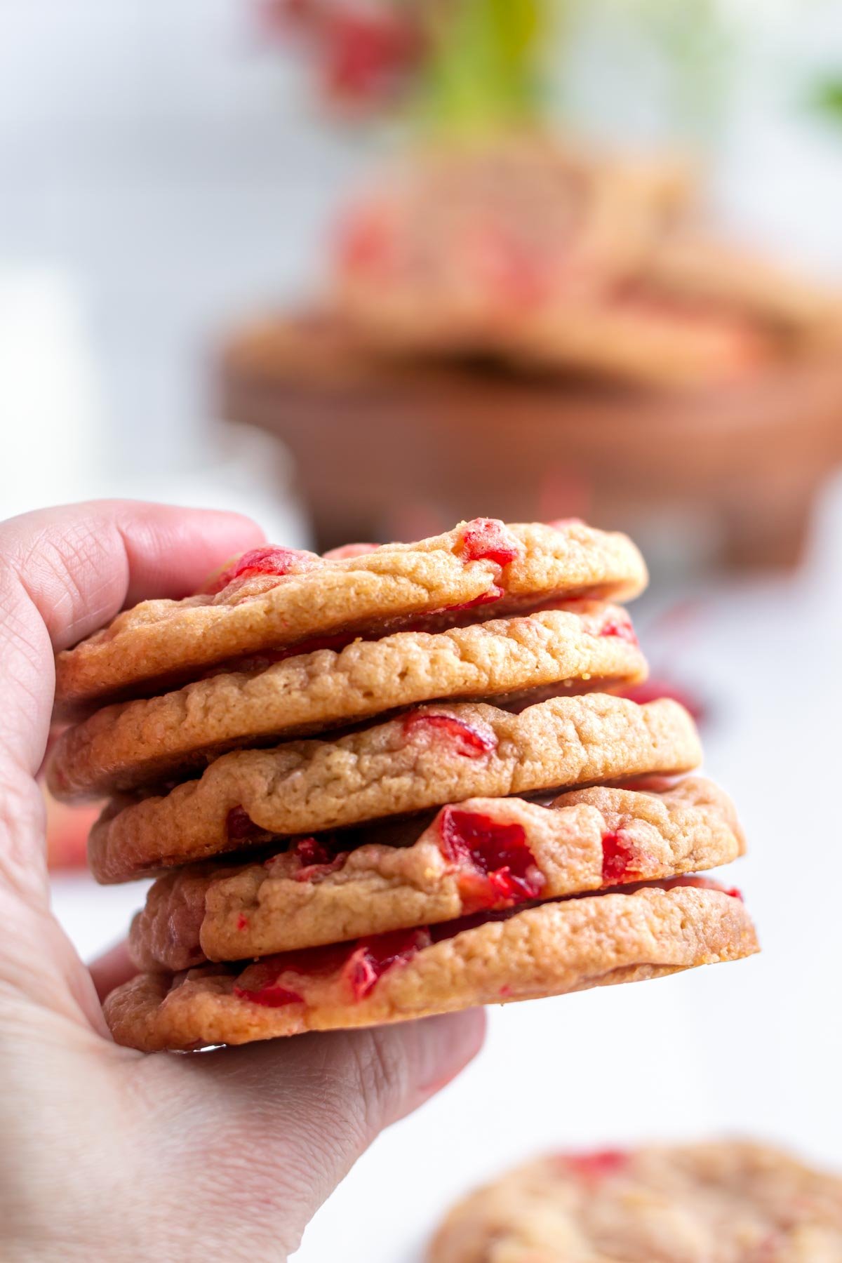 hand holding a stack of cherry almond cookies