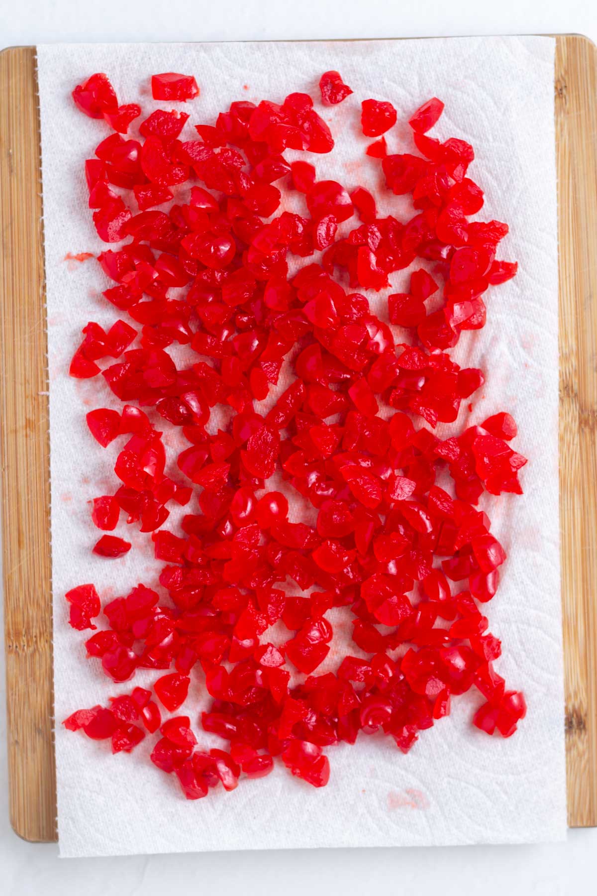 Chopped maraschino cherries on a paper towel lined cutting board.
