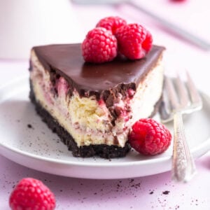 slice of chocolate raspberry cheesecake on a plate with a fork