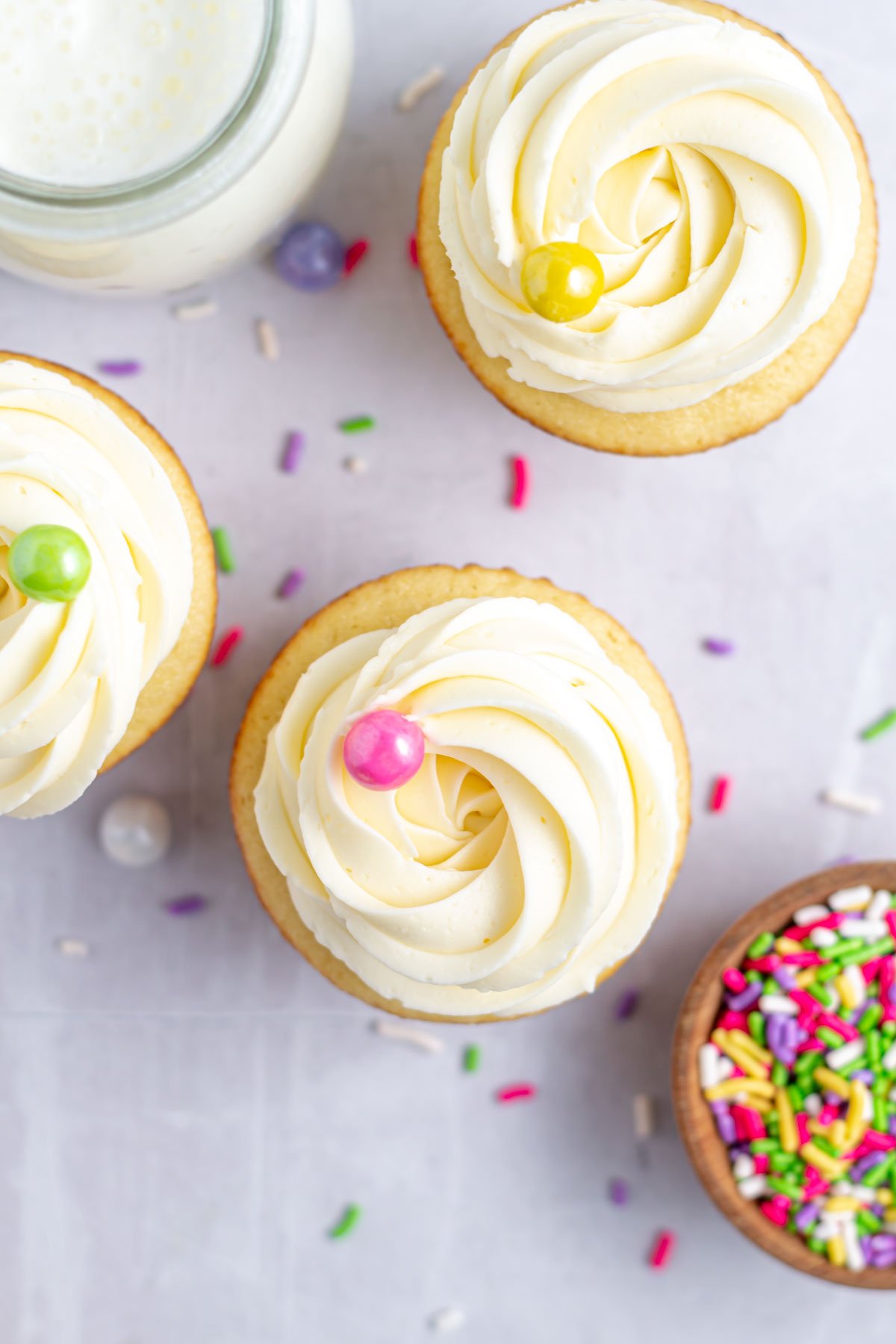 easy vanilla cupcakes swirled with buttercream and topped with colored sprinkles