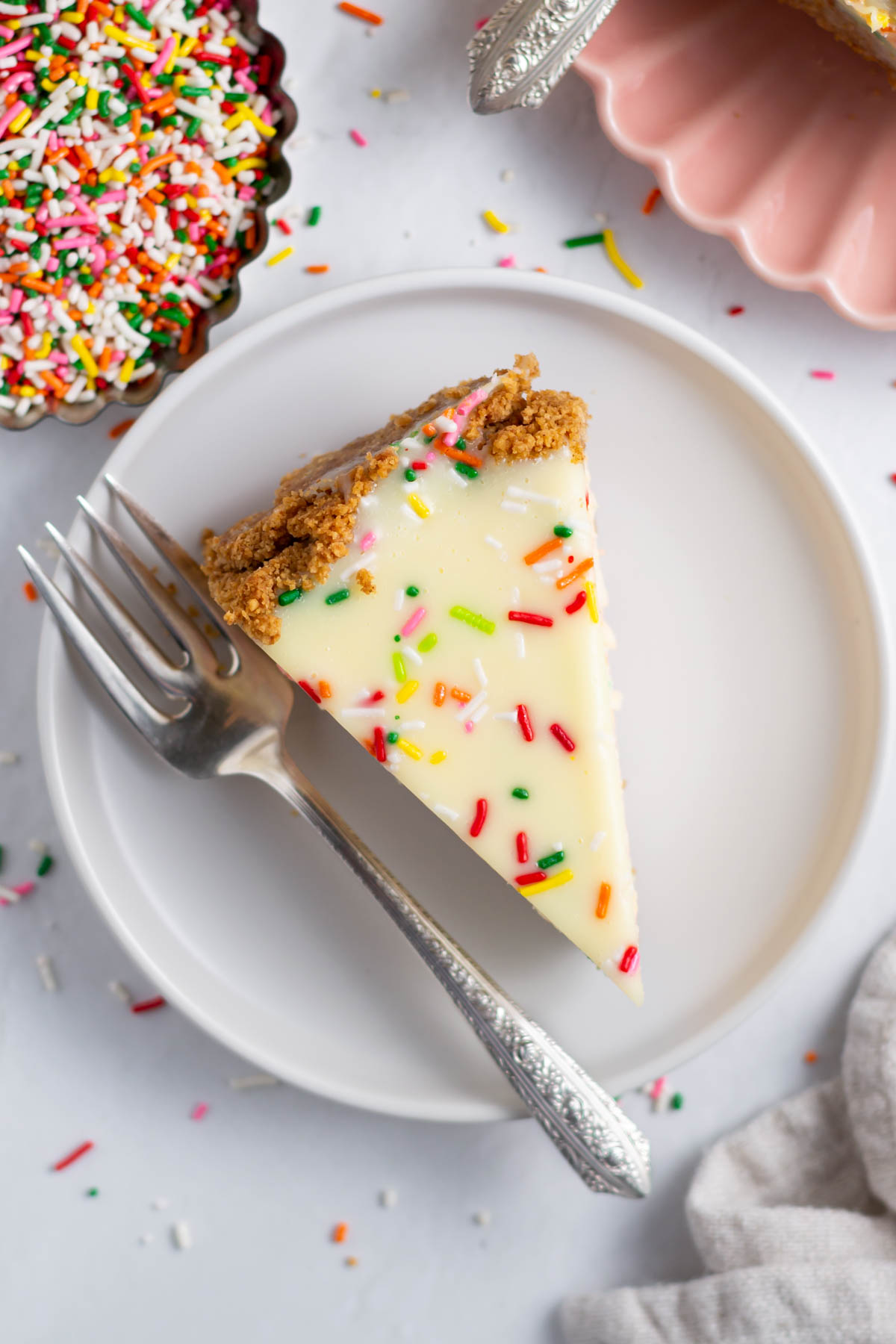 overhead look at white chocolate ganache topping with sprinkles on birthday cheesecake