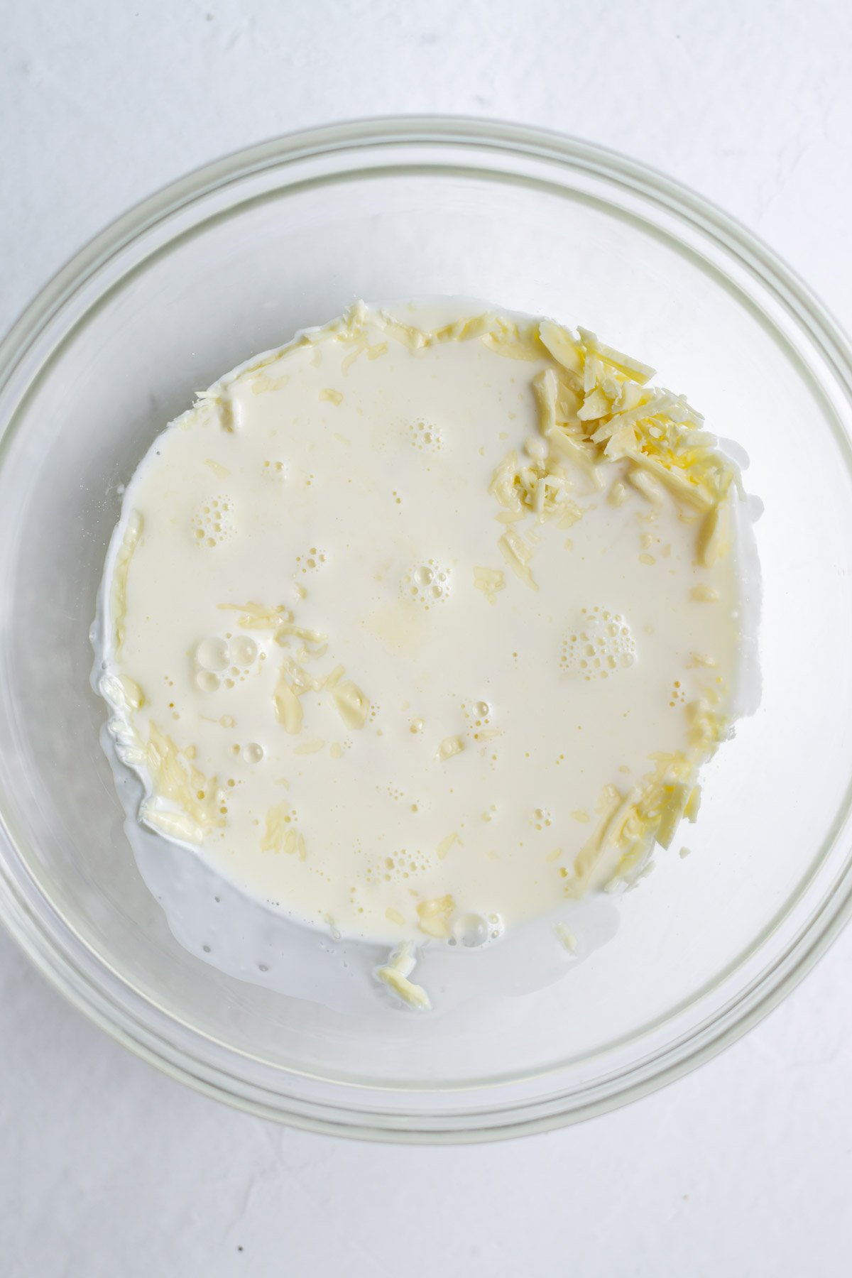 chopped white chocolate with heavy cream in a mixing bowl