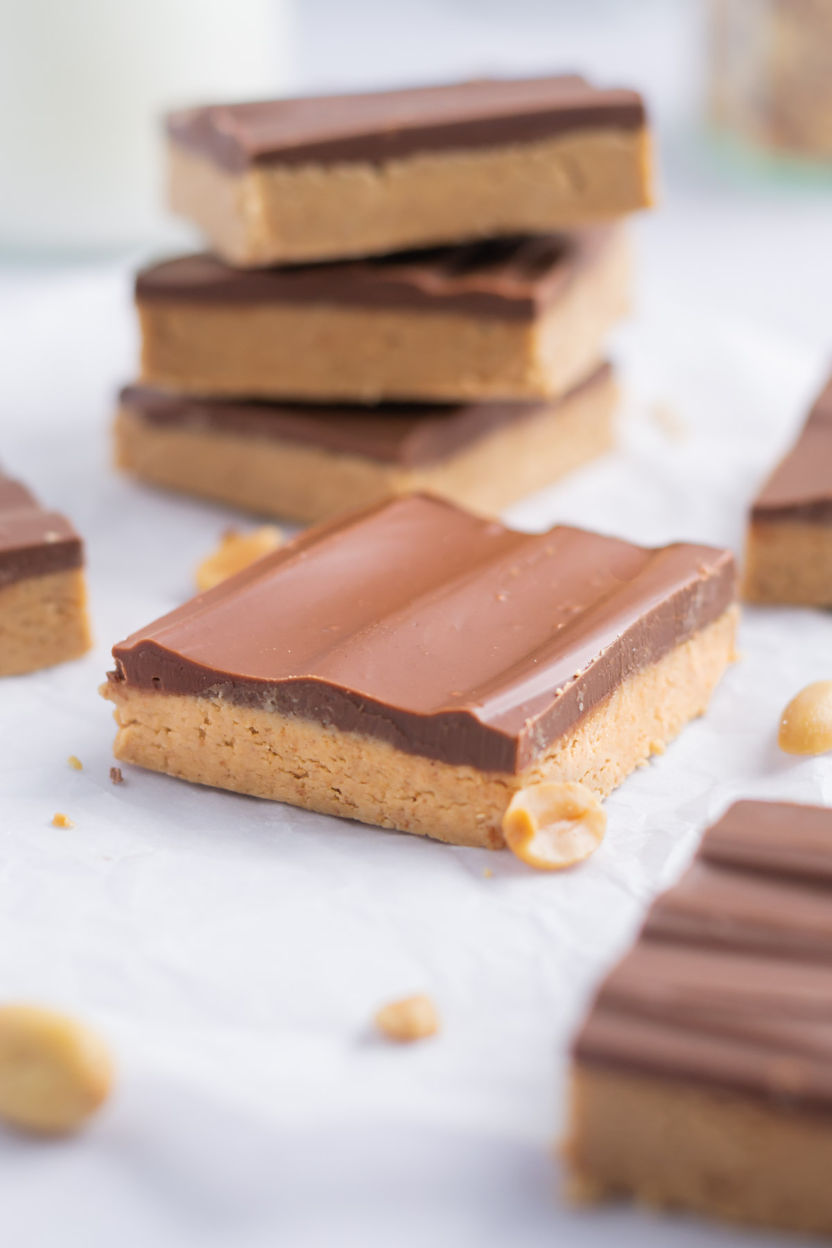 peanut butter bar on parchment with peanuts sprinkled around