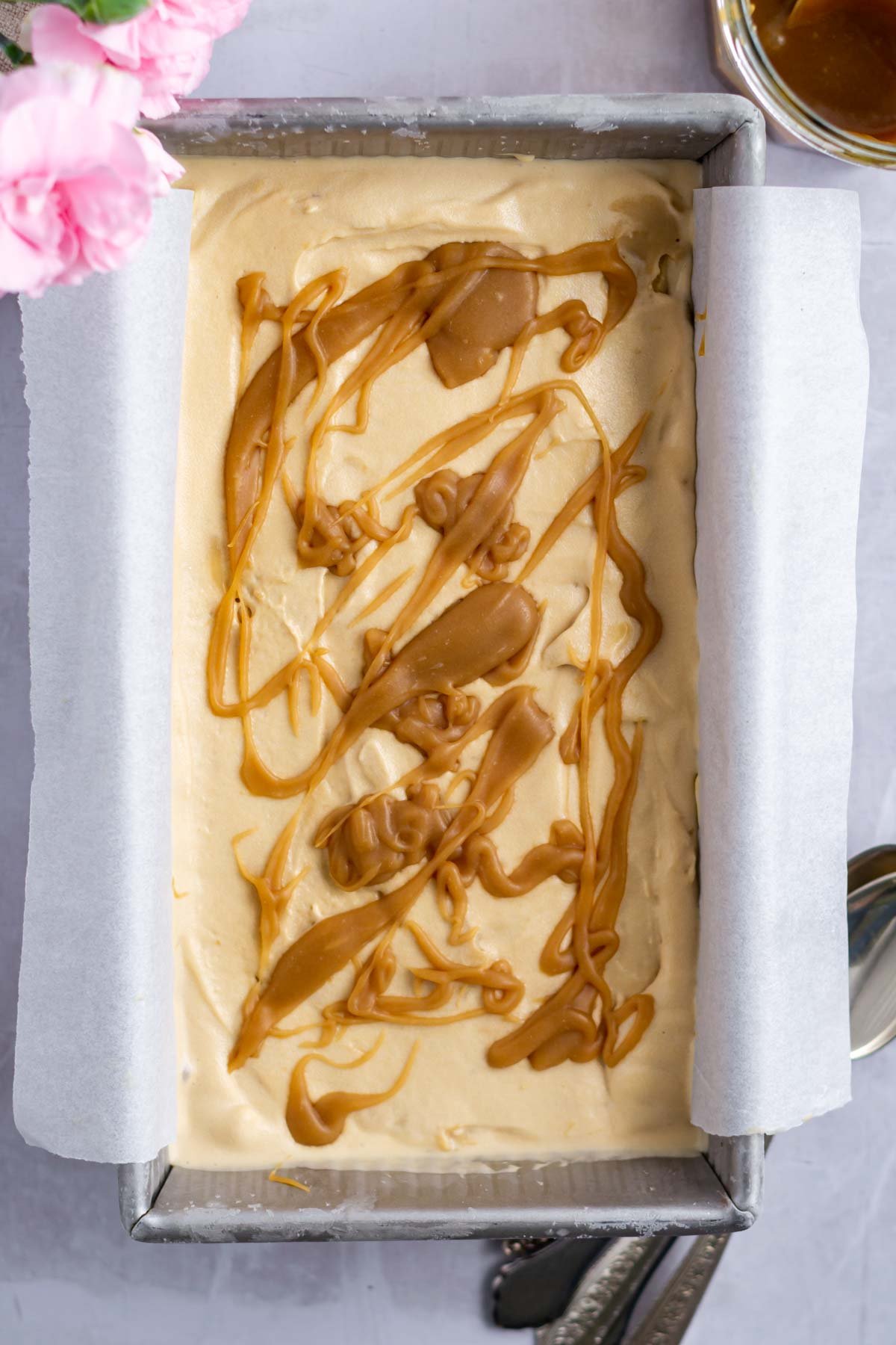 butterscotch ice cream in a loaf pan with homemade butterscotch drizzled over the top.