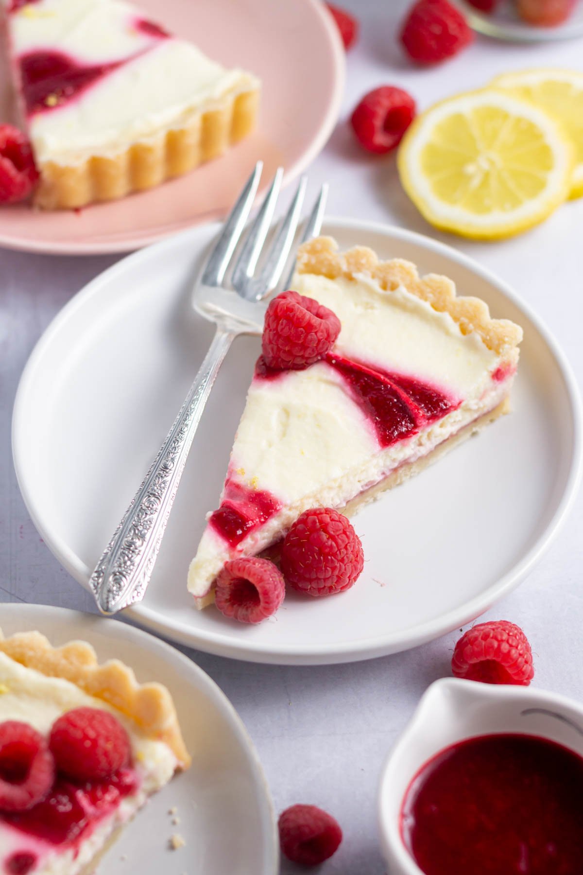 slice of lemon raspberry tart on a plate with a fork