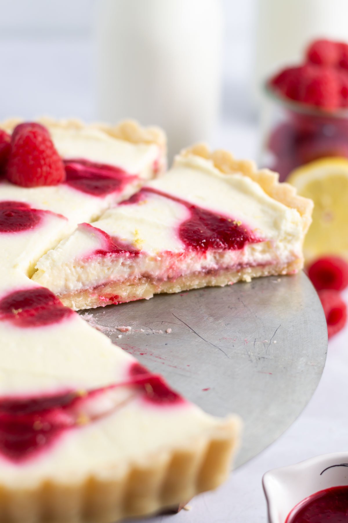 slices of tart showing layers of shortbread crust, lemon filling and raspberry coulis topping