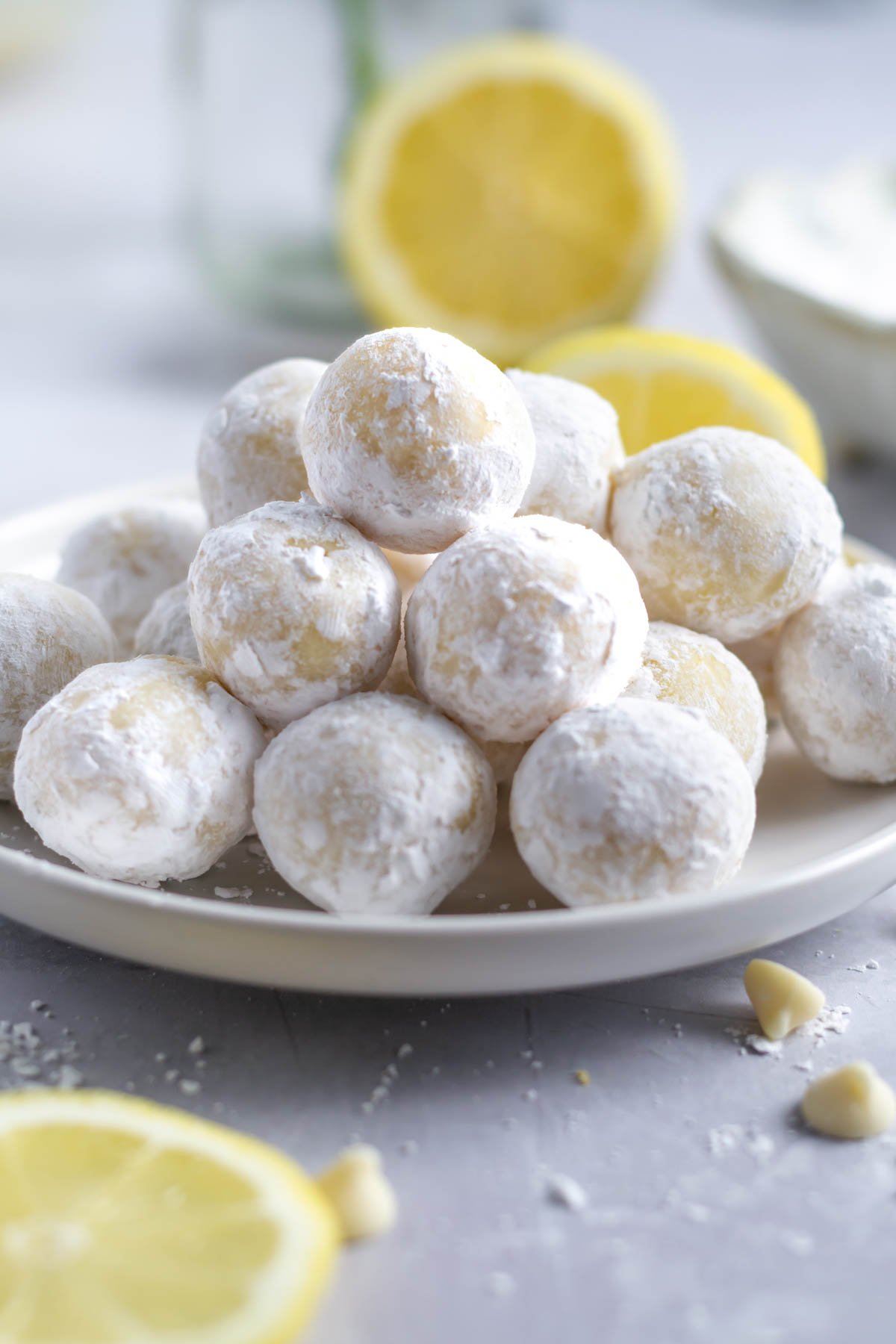 lemon truffles on a plate with lemons in the background