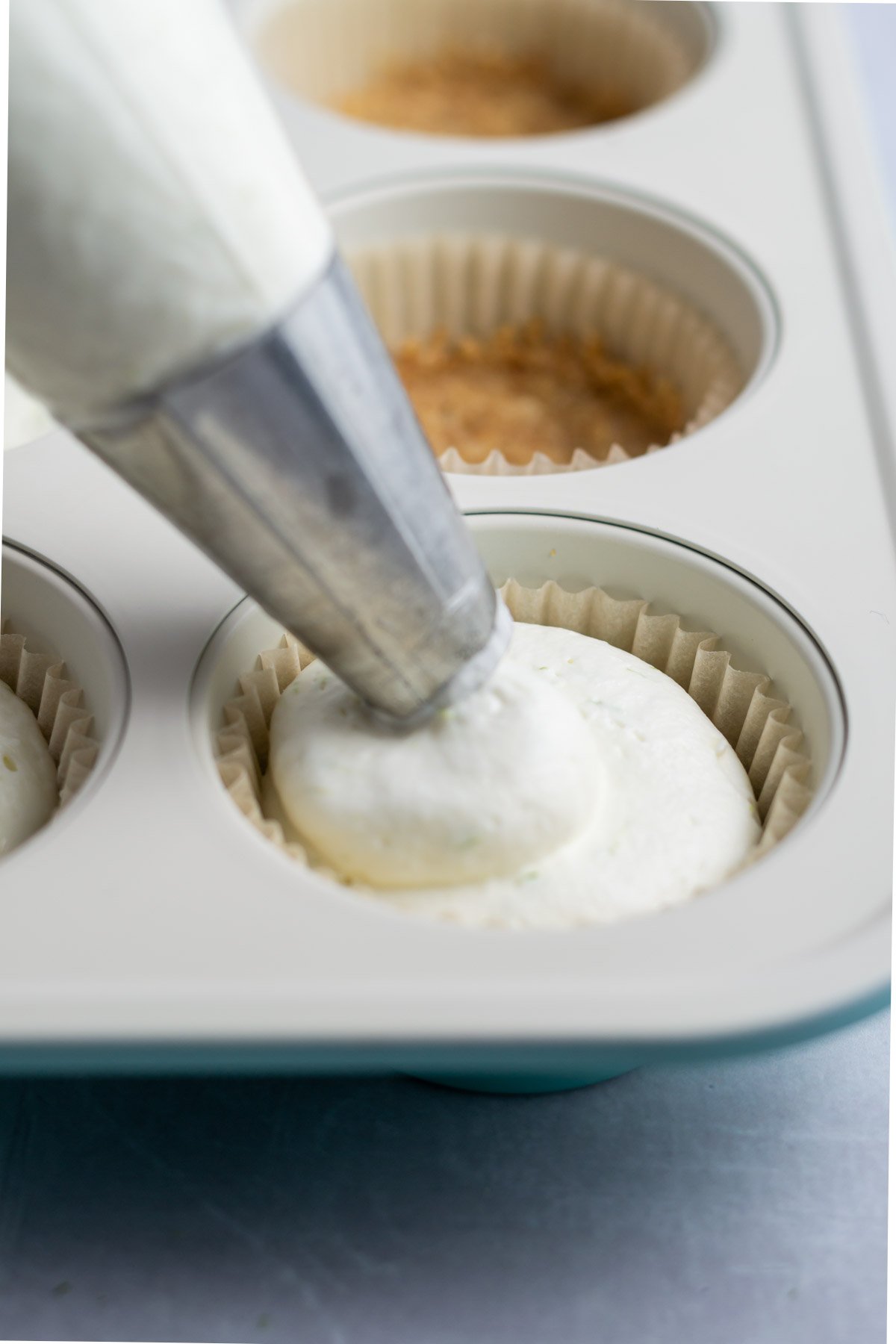 piping bag placing cheesecake into the muffin pan