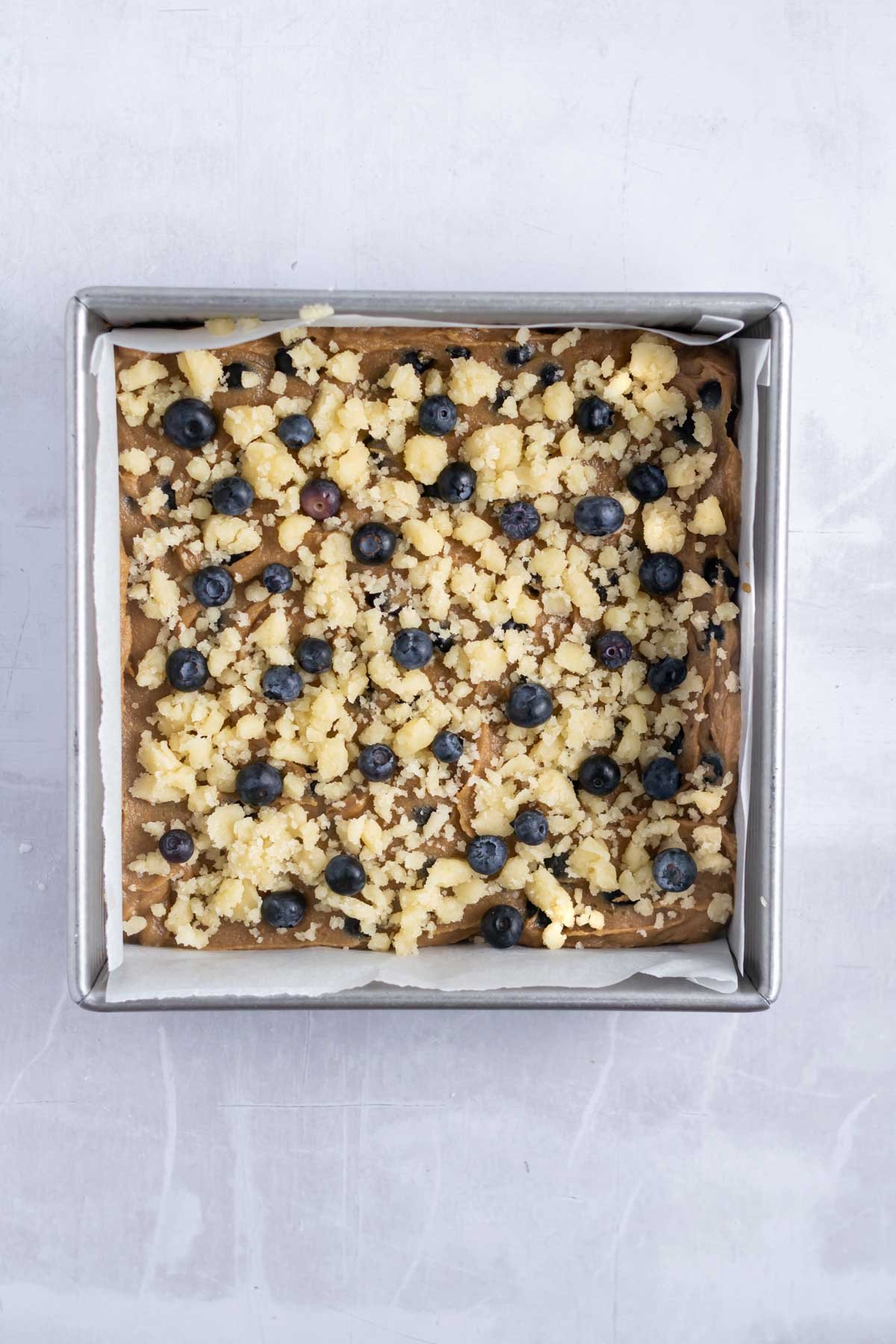 crumble and blueberries sprinkled over the blondie batter