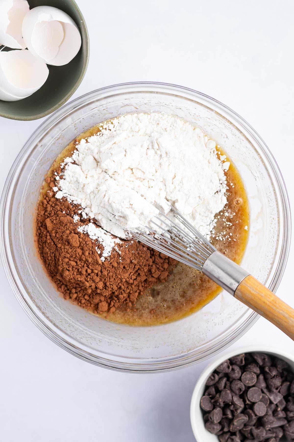 flour and cocoa powder added to wet ingredients in a bowl