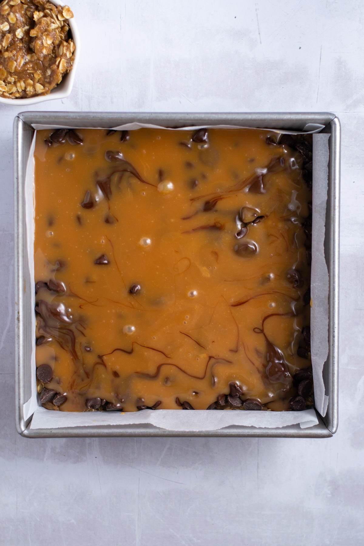 caramel sauce over chocolate chips in a baking square