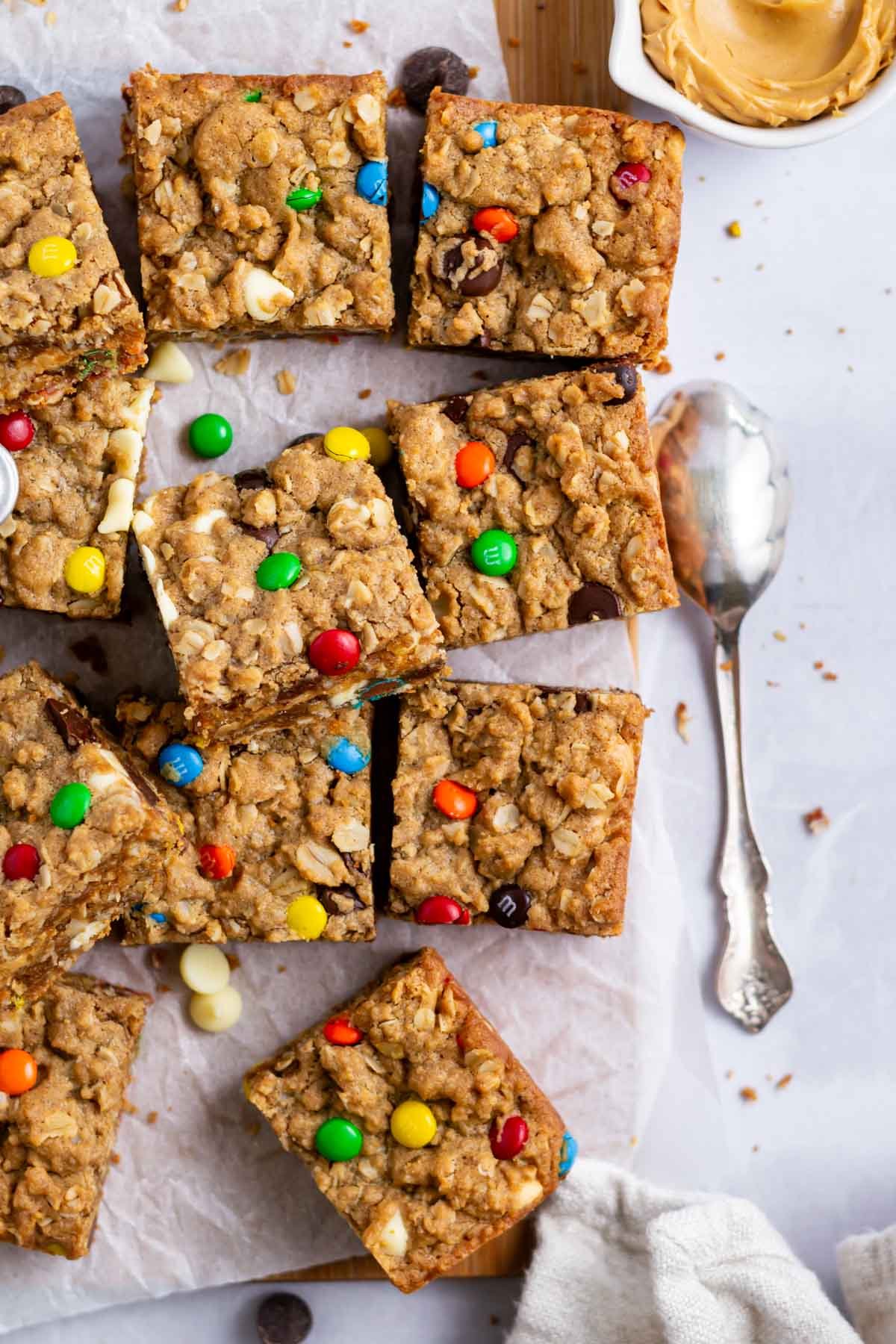 monster cookie bars on parchment paper with a cup of peanut butter