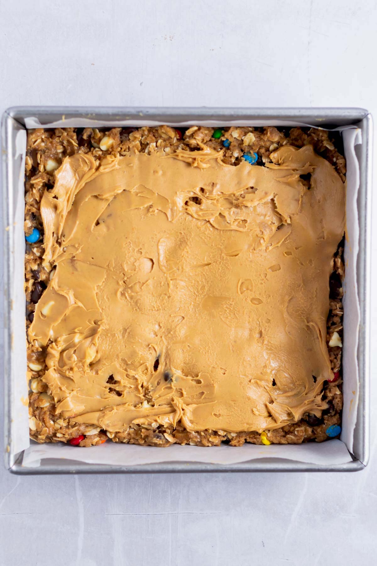 peanut butter layer over bottom layer of cookie dough in a baking pan