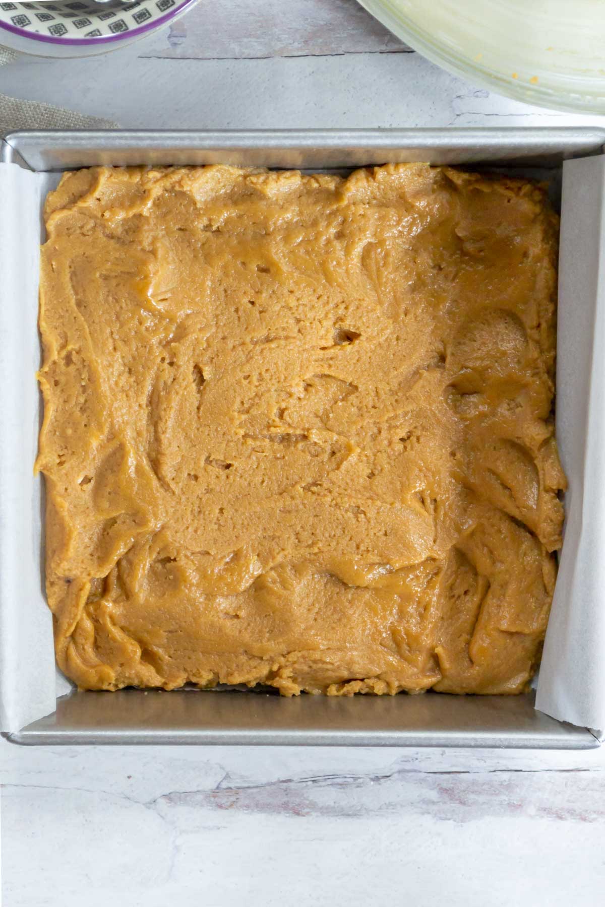 blondie batter smoothed in a parchment lined baking pan.