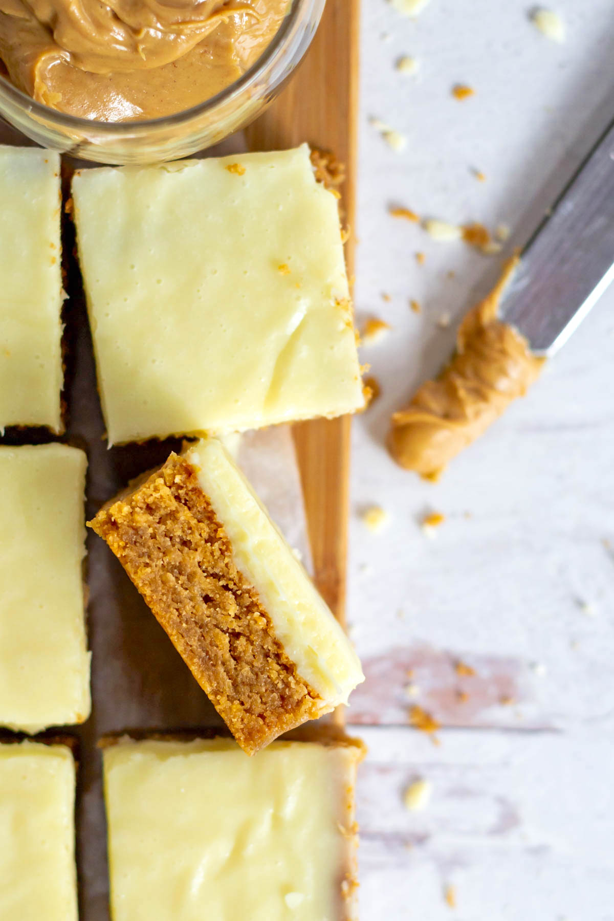 peanut butter blondie with white chocolate ganache on it's side on a cutting board