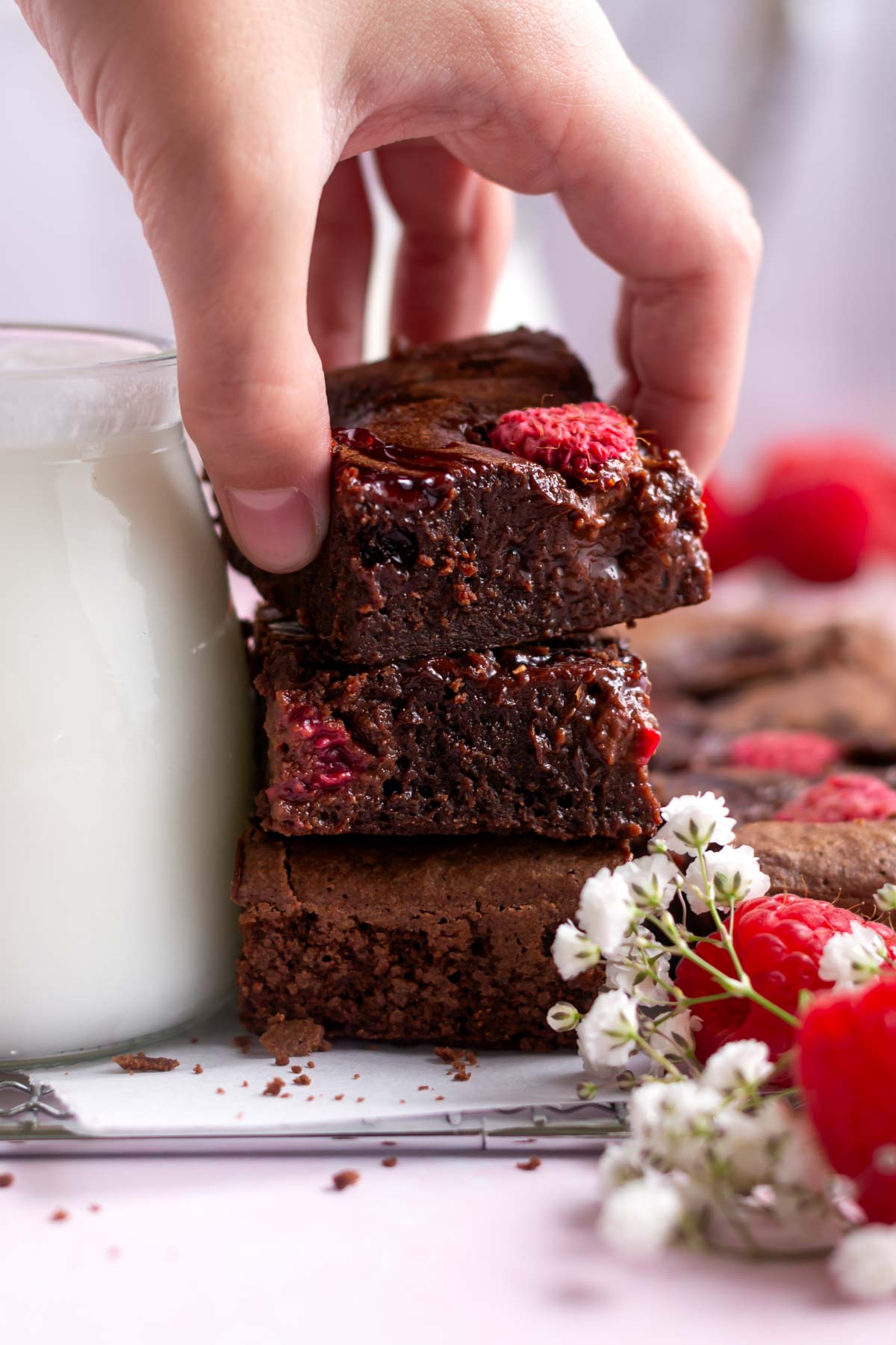 hand grabbing a raspberry brownie from a stack
