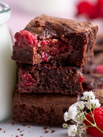 stack of raspberry brownies with a bite missing out of the top one.