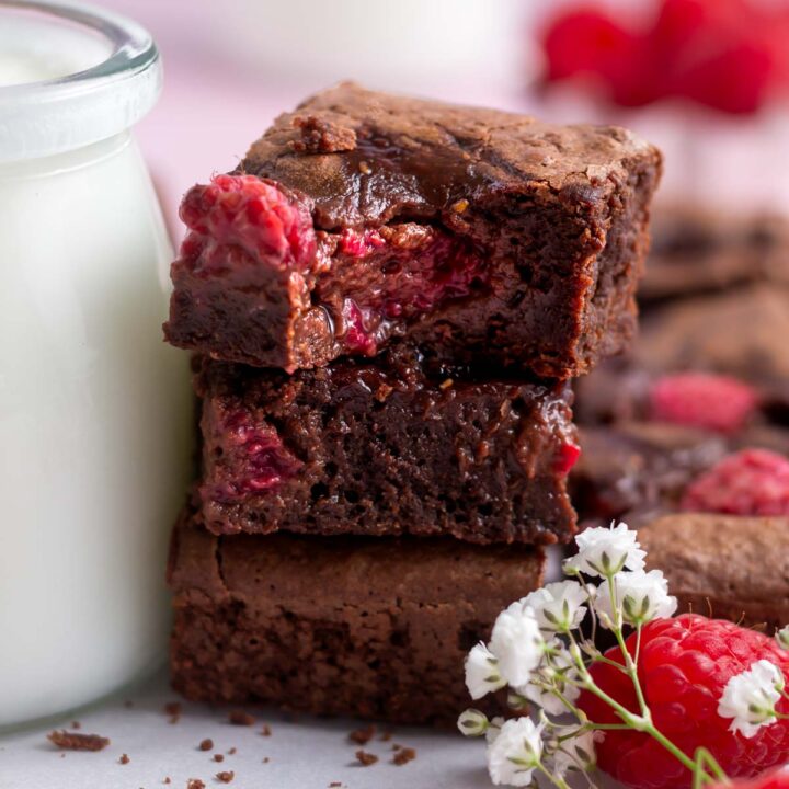 stack of raspberry brownies with a bite missing out of the top one.