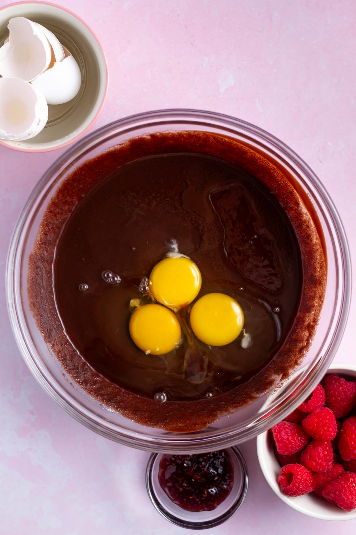 three eggs added to brownie ingredients in a bowl