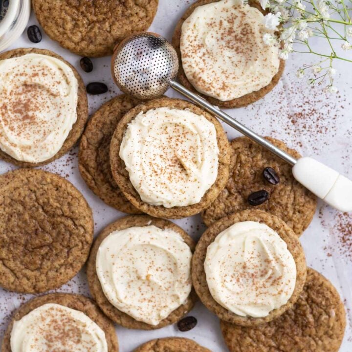 frosted and unfrosted tiramisu cookies on parchment with a cocoa powder duster