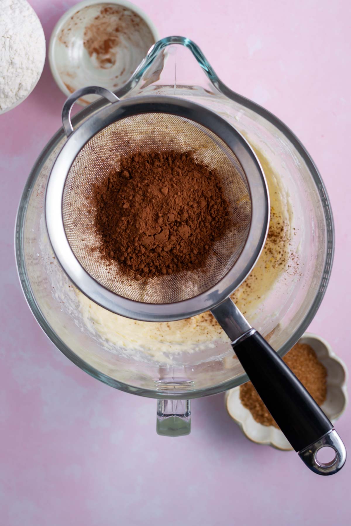 cocoa powder being sifted into a mixing bowl