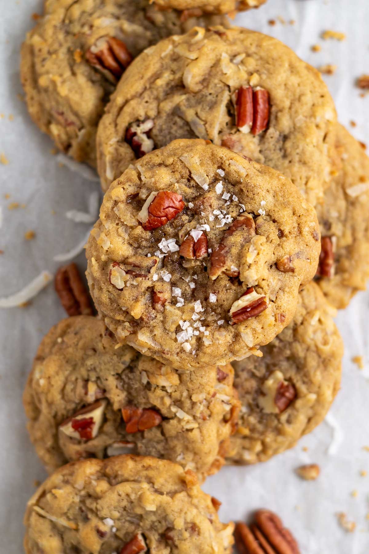 coconut pecan cookies on parchment paper with extra pecans