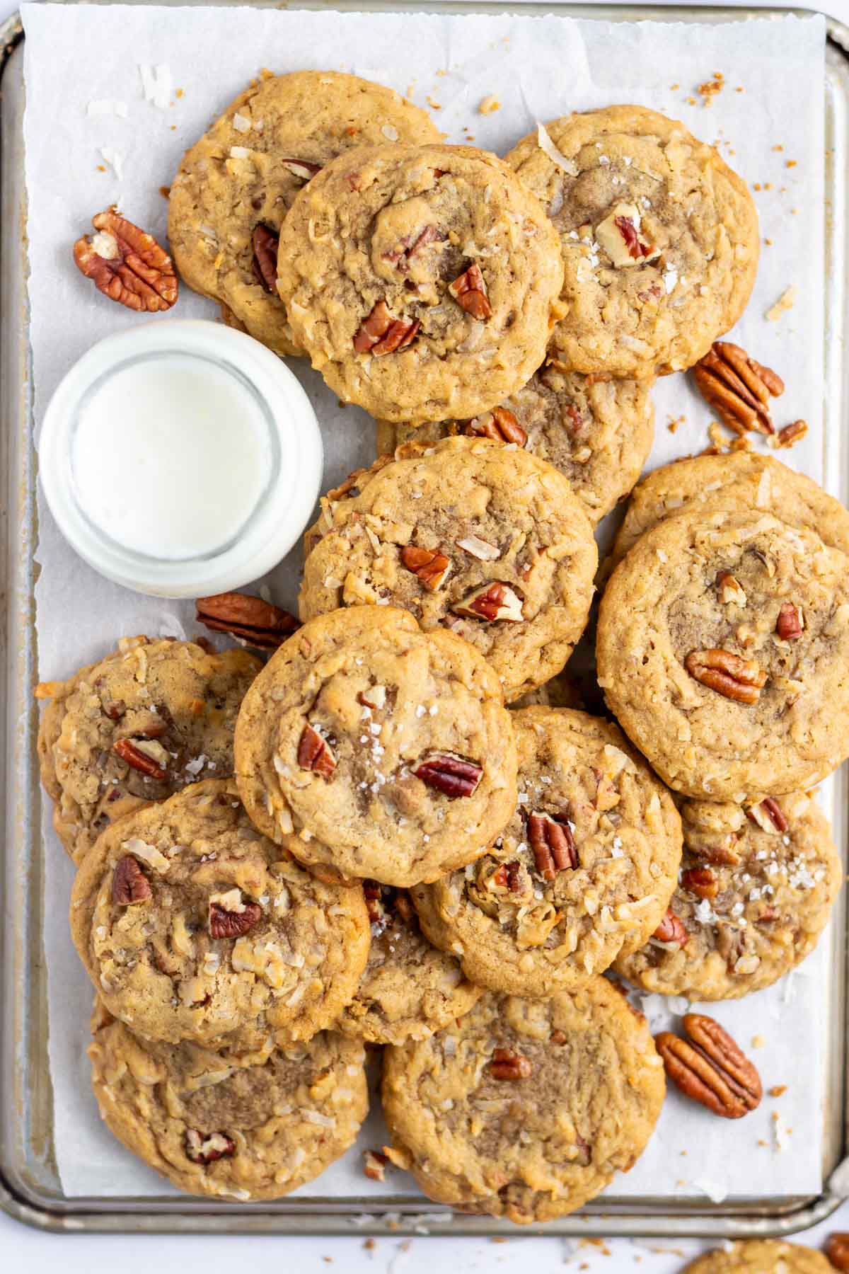 pile of coconut pecan cookies with a glass of milk