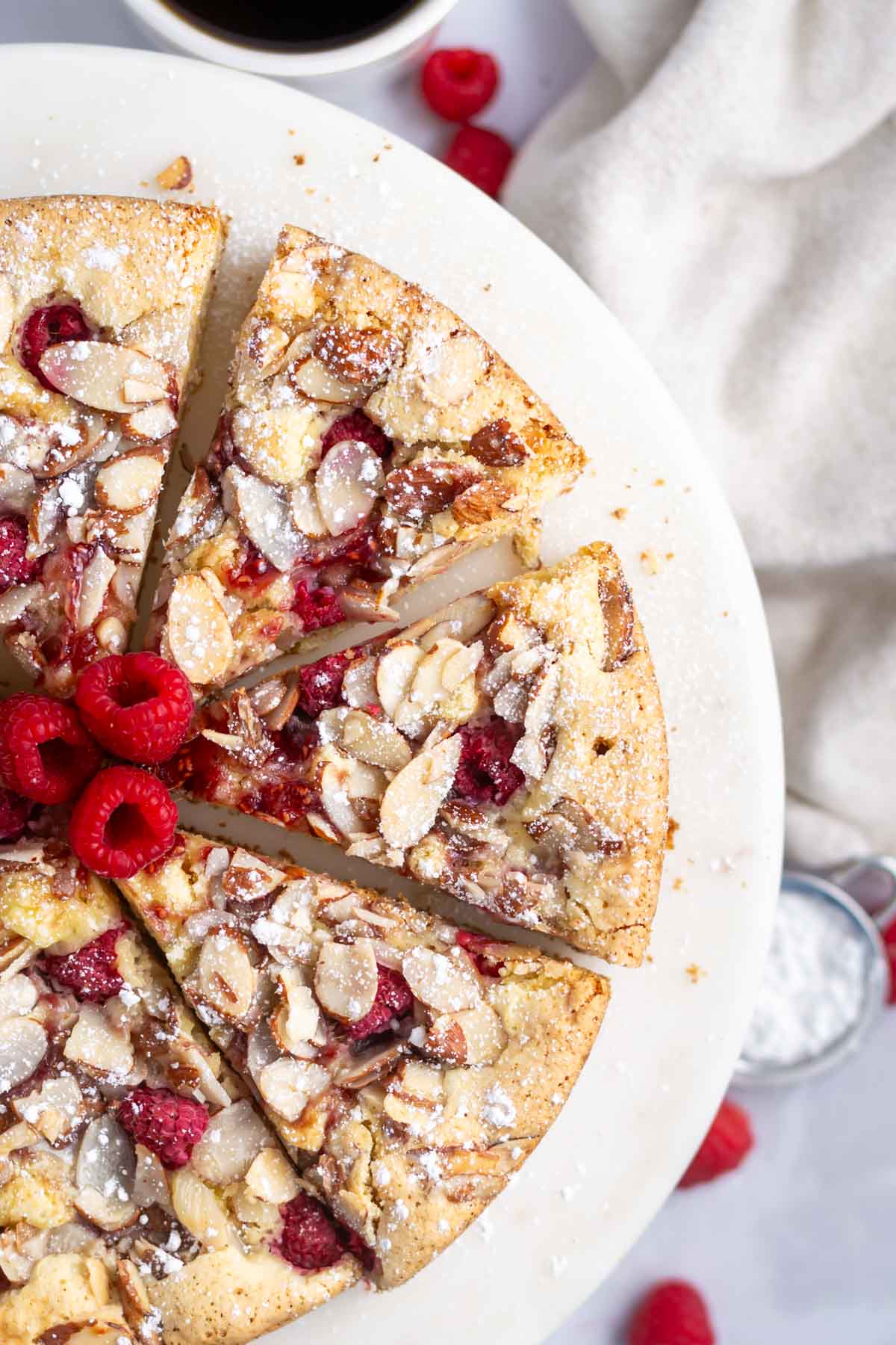 slices of raspberry almond cake on a cake stand