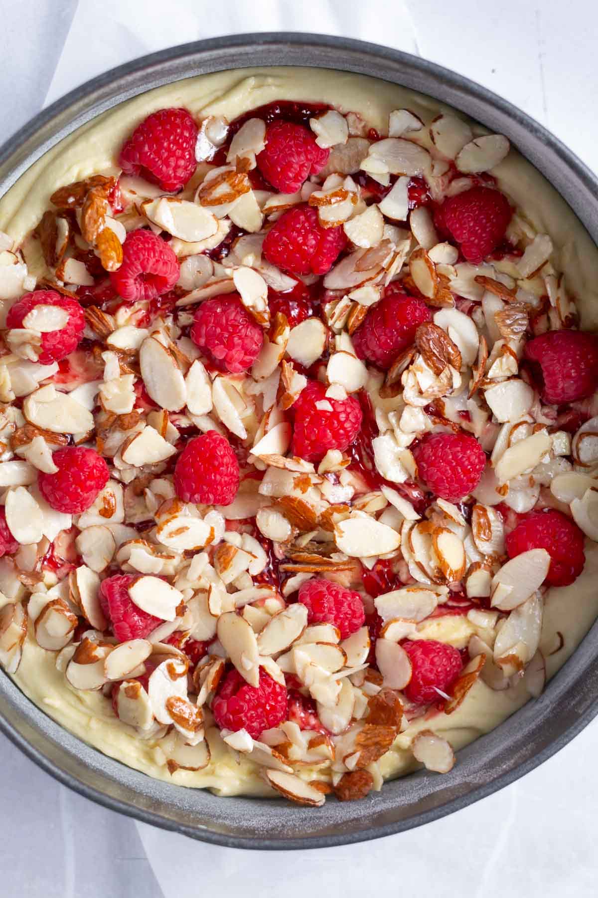 almond slices and fresh raspberries over the cake batter in a springform pan