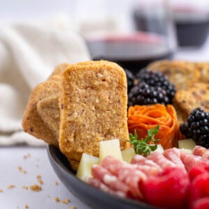 pecan crackers on charcuterie board with a napkin and wine in the background