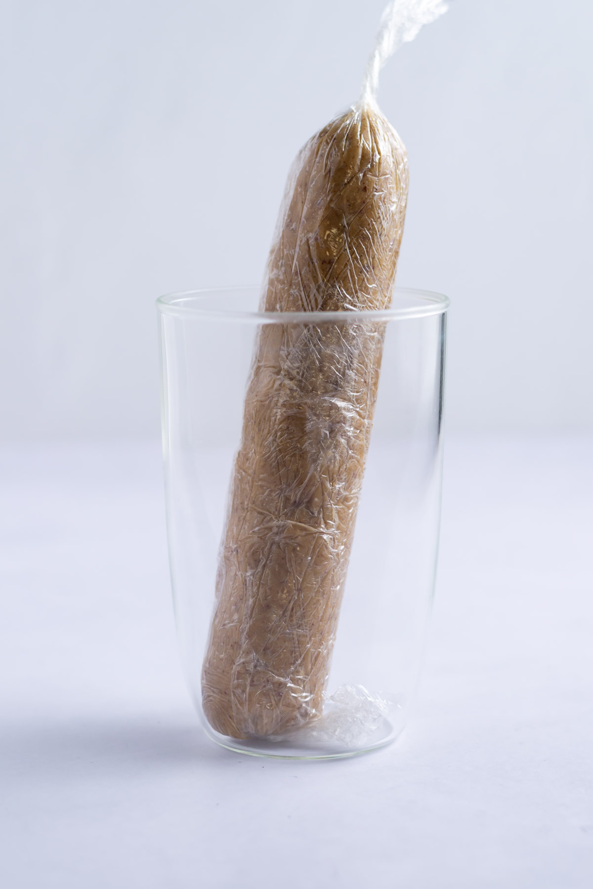 pecan cracker dough wrapped in plastic wrap standing in a tall glass